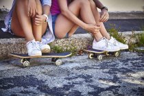 Дві жінки-друзі з ногами на скейтбордах, обрізаний постріл — стокове фото