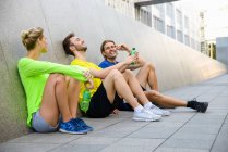 Three friends sitting on floor wearing sports clothing — Stock Photo