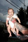 Pai com braços tatuados segurando bebê filho — Fotografia de Stock