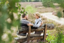 Couple adulte moyen sur banc en bois — Photo de stock