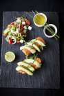 Smoked fish and avocado open sandwiches with salad and dipping sauces, top view — Stock Photo