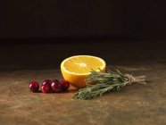 Arancio con mirtilli rossi e rosmarino sulla superficie di marmo — Foto stock