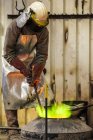 Männlicher Gießereiarbeiter arbeitet mit grün geflammtem Ofen in der Bronzegießerei — Stockfoto