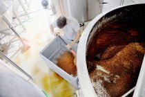 Worker emptying spent grains from mash tun, overhead view — Stock Photo