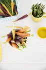 Вид зверху на свіжу різнокольорову моркву та спаржу на кухонному столі — стокове фото