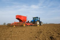 Trattore tirando attrezzature per piantare semi in campo — Foto stock