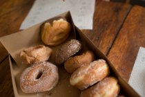 Відкрита коробка з пончиками на дерев'яному столі — стокове фото