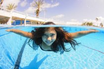 Girl free diving under water in swimming pool — Stock Photo