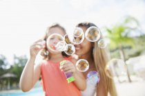 Mother and daughter blowing soap bubbles — Stock Photo