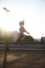 Sunlit silhouette of young female skipping on rooftop — Stock Photo