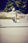 Маленький хлопчик в шоломі скейтбординг в парку — стокове фото