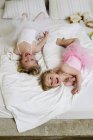 Porträt zweier kleiner Schwestern, die auf dem Bett spielen — Stockfoto