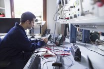 Электрик-мужчина ремонтирует электронное оборудование в мастерской — стоковое фото
