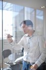 Man drawing architectural plans on glass wall — Stock Photo