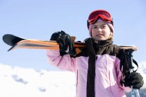 Chica con esquís en el hombro - foto de stock