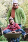 Father pushing son in wheelbarrow, laughing — Stock Photo