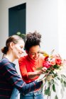 Дві усміхнені жінки роблять букет у магазині флористів — стокове фото