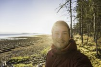 Retrato iluminado por el sol del hombre en el Parque Provincial de Rathrevor Beach, Isla Vancouver, Columbia Británica, Canadá - foto de stock
