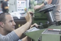 Caucasian adult man checking rotary blade on grinding machine — Stock Photo