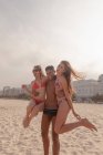 Молодой человек перевозит двух женщин вместе на пляже Копакабана, Рио-де-Жанейро, Бразилия — стоковое фото