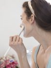Взрослая женщина, увлажняющая лицо кистью для макияжа — стоковое фото