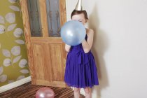Girl blowing up blue balloon — Stock Photo