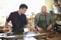 Deux travailleurs masculins en atelier de cuir, vérifiant les ceintures en cuir — Photo de stock
