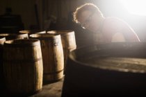 Junger Mann arbeitet in Küferei mit Whiskyfässern — Stockfoto