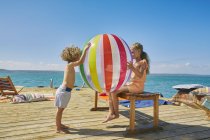 Мальчик и девочка играют с пляжным мячом на плавучей солнечной палубе, Краальбай, Южная Африка — стоковое фото