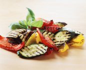 Продукты питания, приготовленные овощи, жареные кабачки, красный перец, желтый перец, листья базилика — стоковое фото
