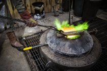 Чоловічий ливарник нагріває бронзове злиття над печею в бронзовому ливарному виробництві — стокове фото