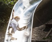 Хлопчик ковзає вниз дитячий майданчик слайд — стокове фото