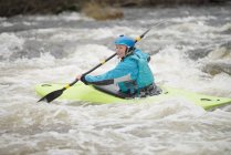 Jeune kayakiste femelle pagayant sur les rapides de la rivière Dee — Photo de stock