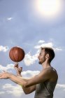 Joven jugador de baloncesto masculino haciendo girar la pelota en el dedo - foto de stock