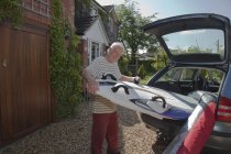 Старший чоловік видаляє дошку для серфінгу з багажника — стокове фото