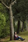 Ragazza adolescente seduta contro l'albero nella foresta — Foto stock