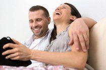 Середня доросла пара, дивлячись на цифровий планшет разом — стокове фото