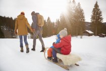 Visão traseira dos pais puxando filhos em tobogã na paisagem da neve, Elmau, Baviera, Alemanha — Fotografia de Stock