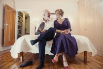 Paar sitzt auf dem Bett, Mann zieht Schuhe an und schaut Frau an — Stockfoto