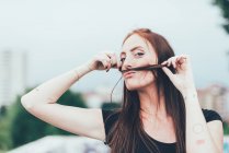 Portrait of young woman with freckles making mustache with long red hair — Stock Photo