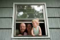Famiglia guardando attraverso la finestra — Foto stock
