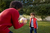 Father and son playing with football in garden smiling — Stock Photo
