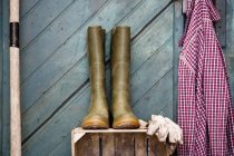 Botas de borracha, luvas de jardinagem e camisa por galpão — Fotografia de Stock