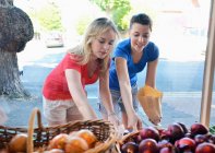 Dos mujeres jóvenes eligiendo comida en el puesto del mercado - foto de stock