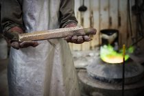 Mittlerer Abschnitt eines männlichen Gießereiarbeiters mit einem Bronzenbarren in der Bronzegießerei — Stockfoto