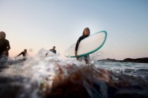 Four people with surfboards in the water — Stock Photo