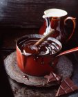 Geschmolzene Vollmilchschokolade im roten Vintage-Topf — Stockfoto