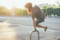 Молодой хипстер поднимает каблуки на освещенном солнцем тротуаре — стоковое фото