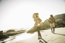 Pais dando às crianças passeio de piggyback na praia — Fotografia de Stock