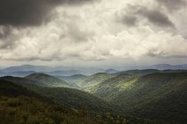 Verdes montañas cubiertas bajo el cielo nublado - foto de stock